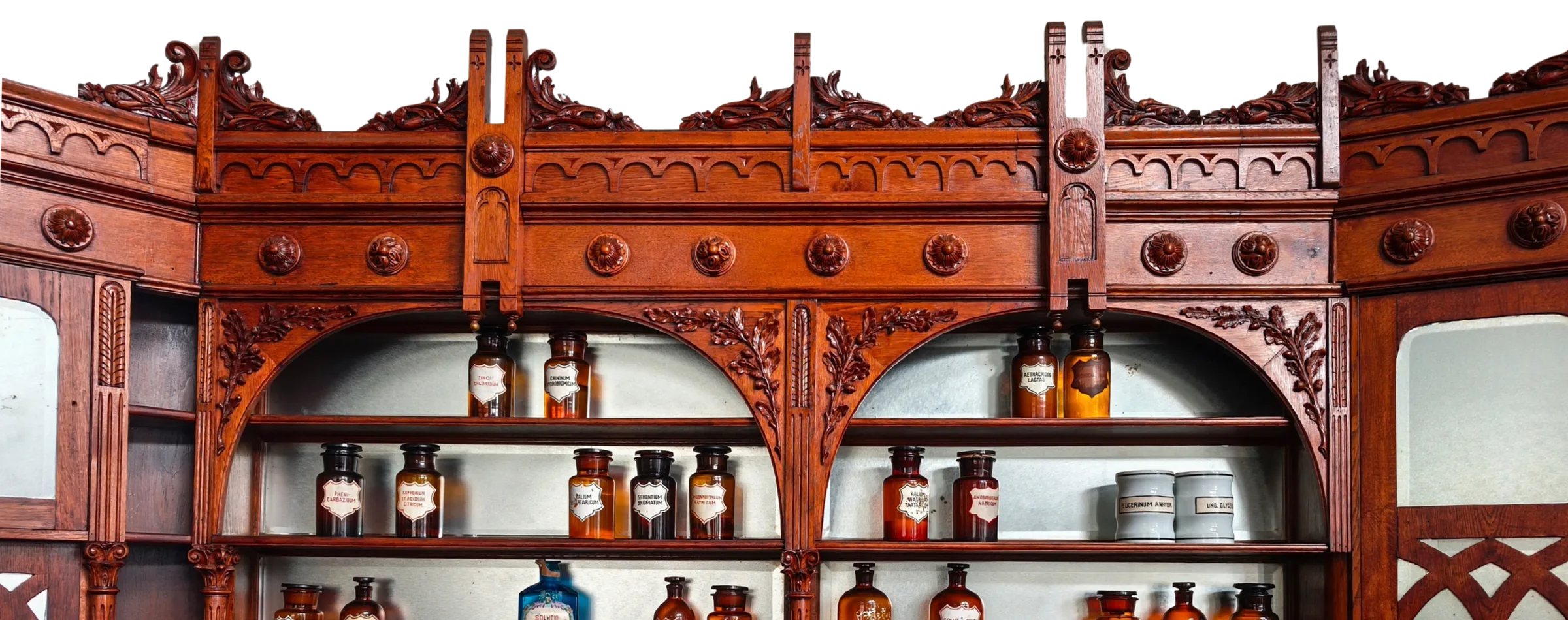 An antique carved-wood apothecary cabinet lined with old labelled jars