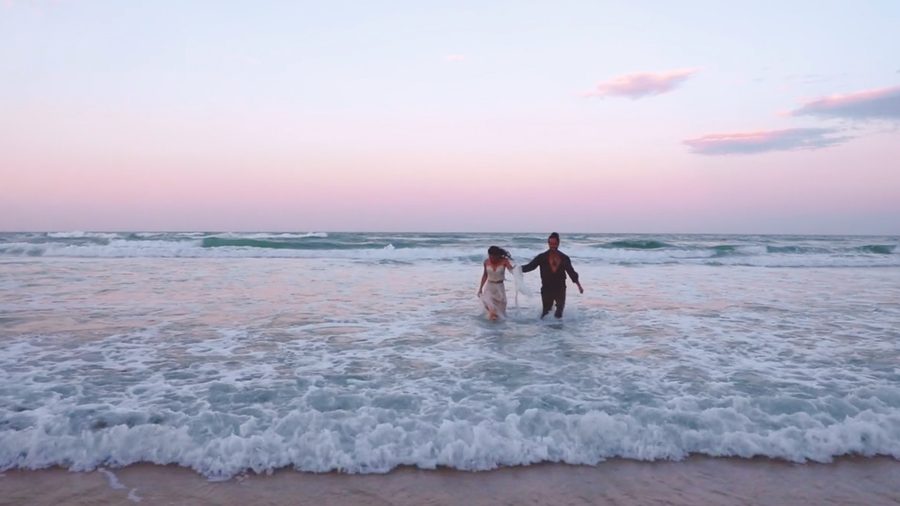 An elopement couple frolicking in the ocean after being married